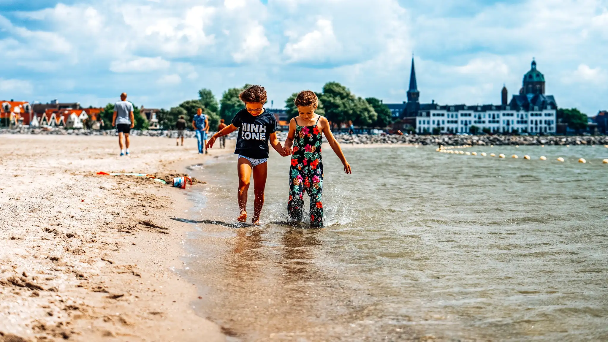 Twee kinderen hand in hand over het strand bij Markermeer